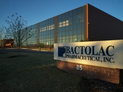 Exterior view of bactolac pharmaceutical, inc. building with large glass facade; company sign in foreground.